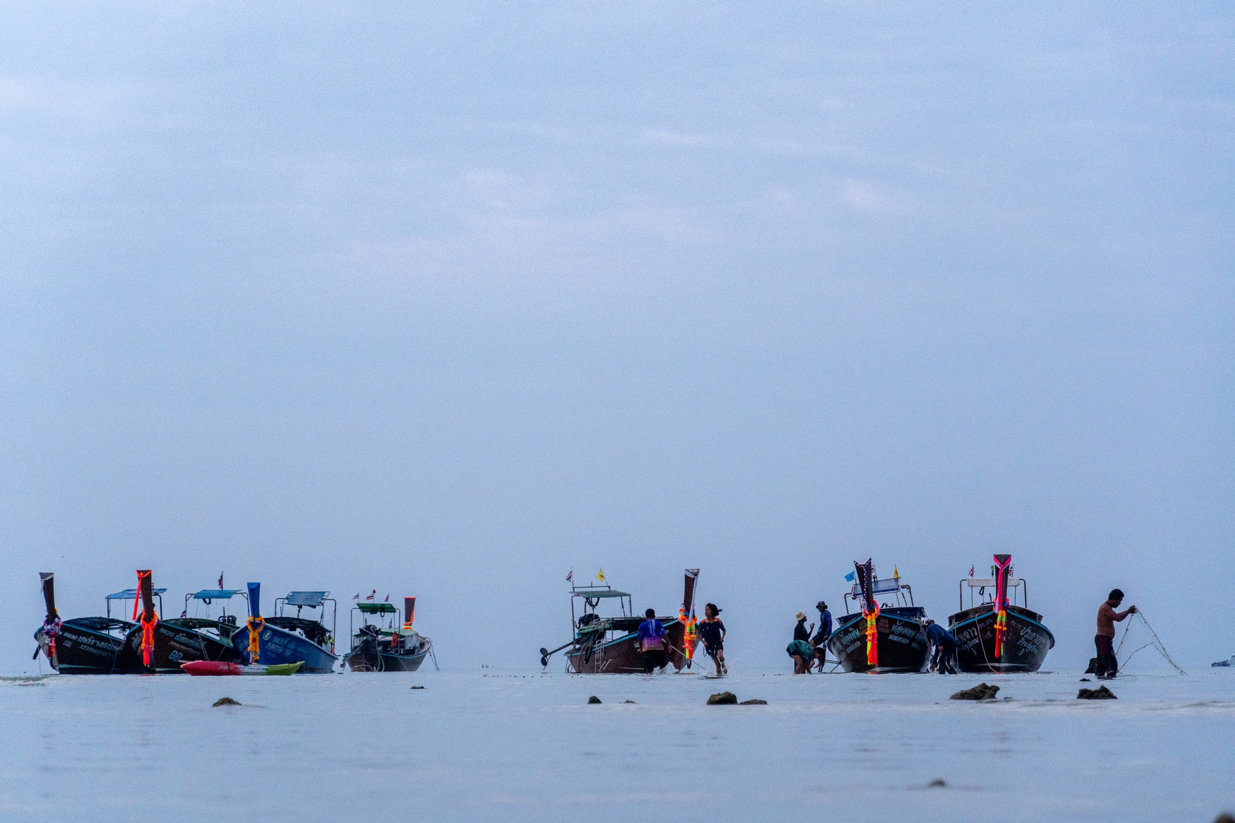 Pescador trabalhando com rede próximo ao barco em Koh Phi Phi